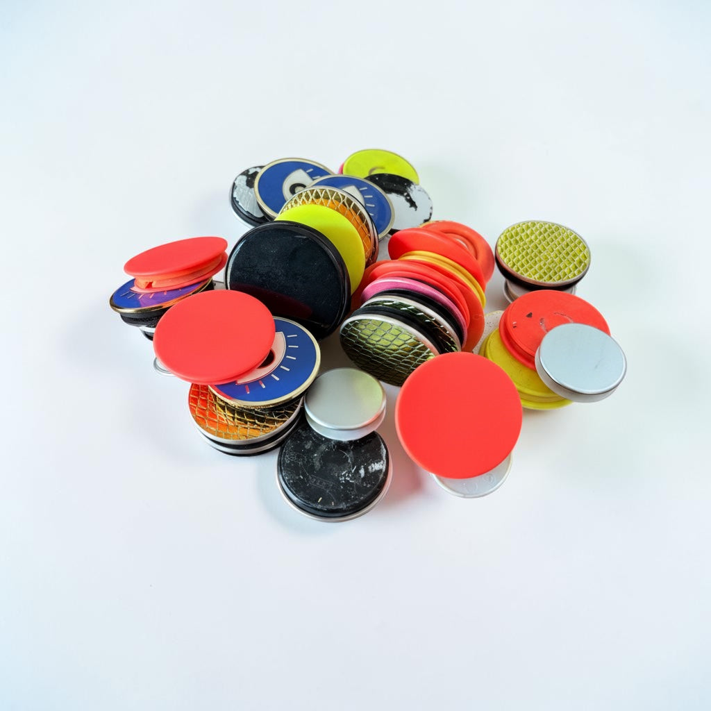 Outrageous Art assorted collapsible phone grips and stands in various vibrant colors, metallic finishes, and patterns.
