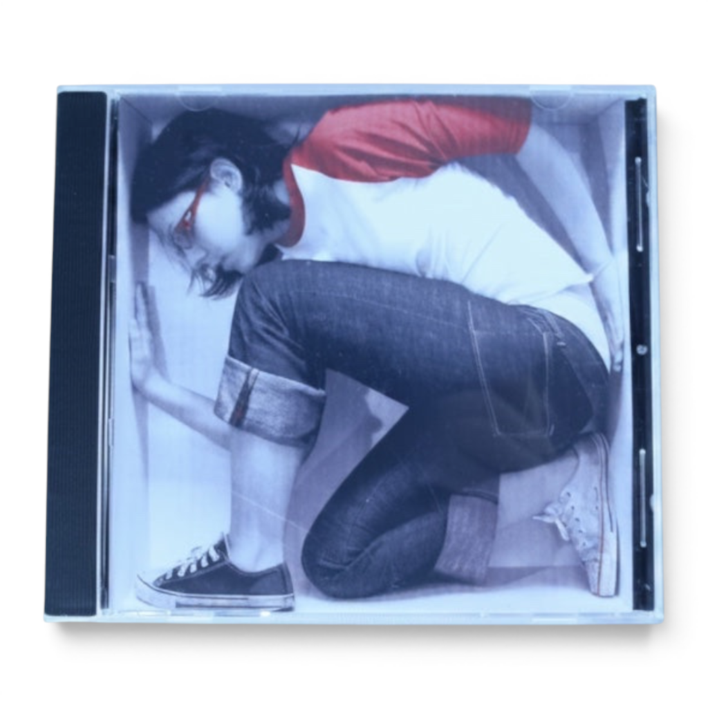 Outrageous Art Ali Spagnola debut album CD featuring cover art of a woman in a box wearing a red and white shirt.