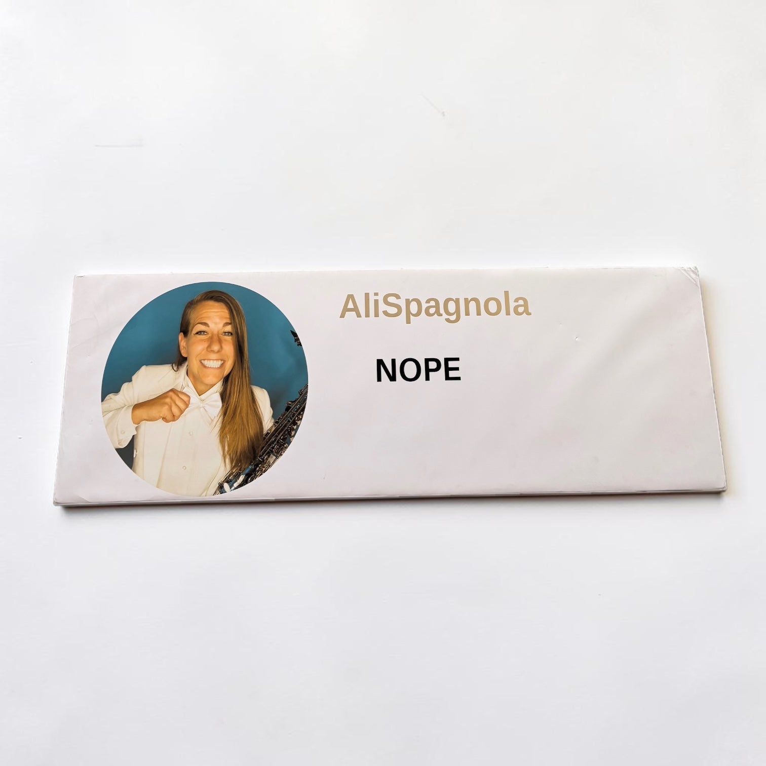 Outrageous Art prop comment featuring Ali Spagnola in a white suit with the text NOPE on a white rectangular sign.
