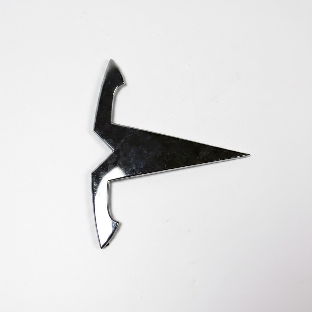 Outrageous Art metallic automotive emblem with a polished chrome finish for electric vehicle exterior styling.