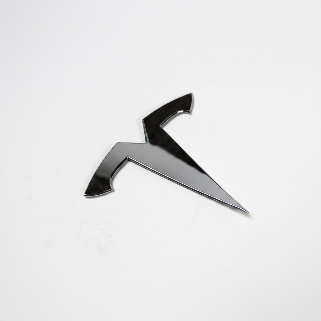 Outrageous Art chrome-finish T-logo automotive emblem for electric vehicles with a sleek, reflective surface.