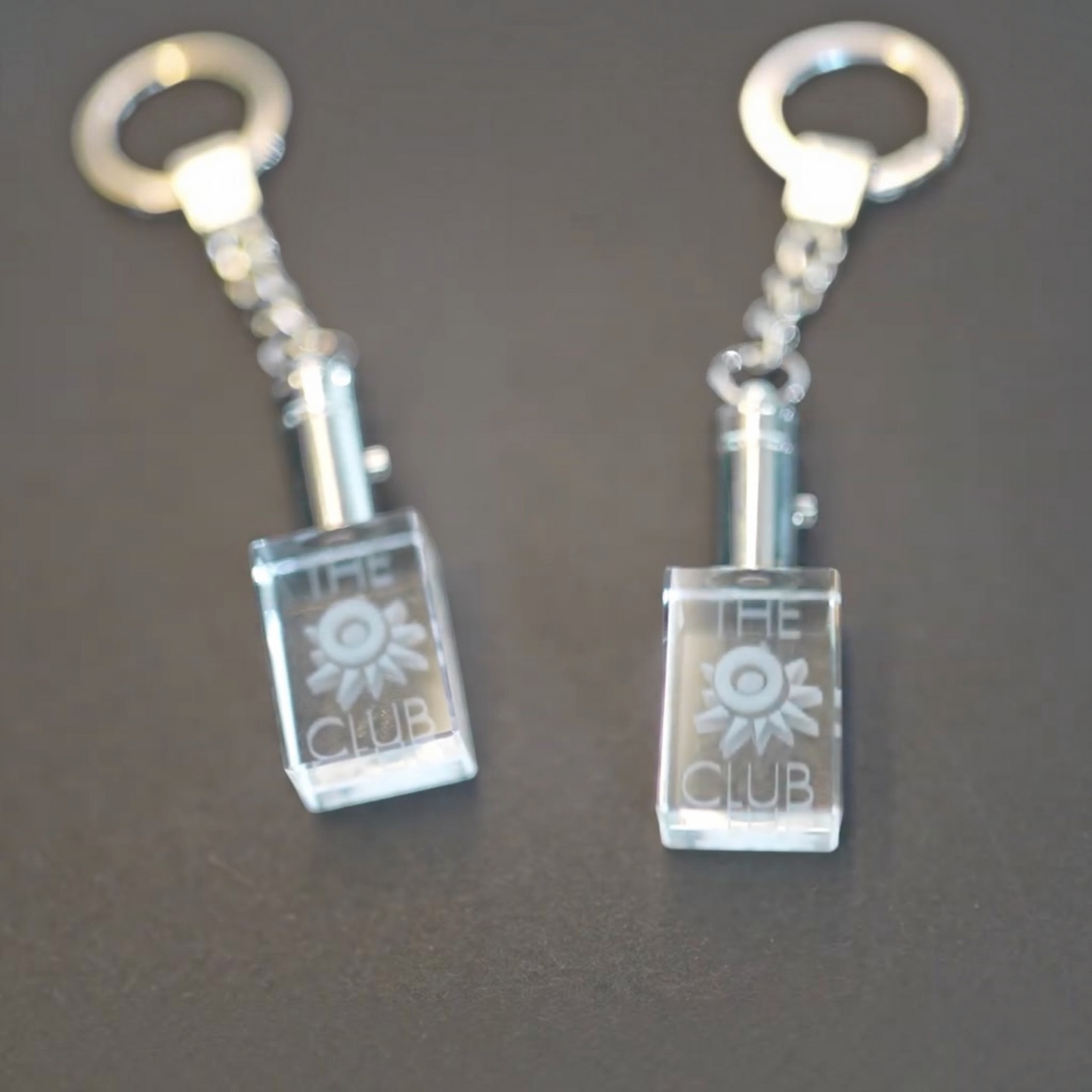Outrageous Art O Club keychain featuring a clear rectangular crystal block with engraved logo and polished metal chain