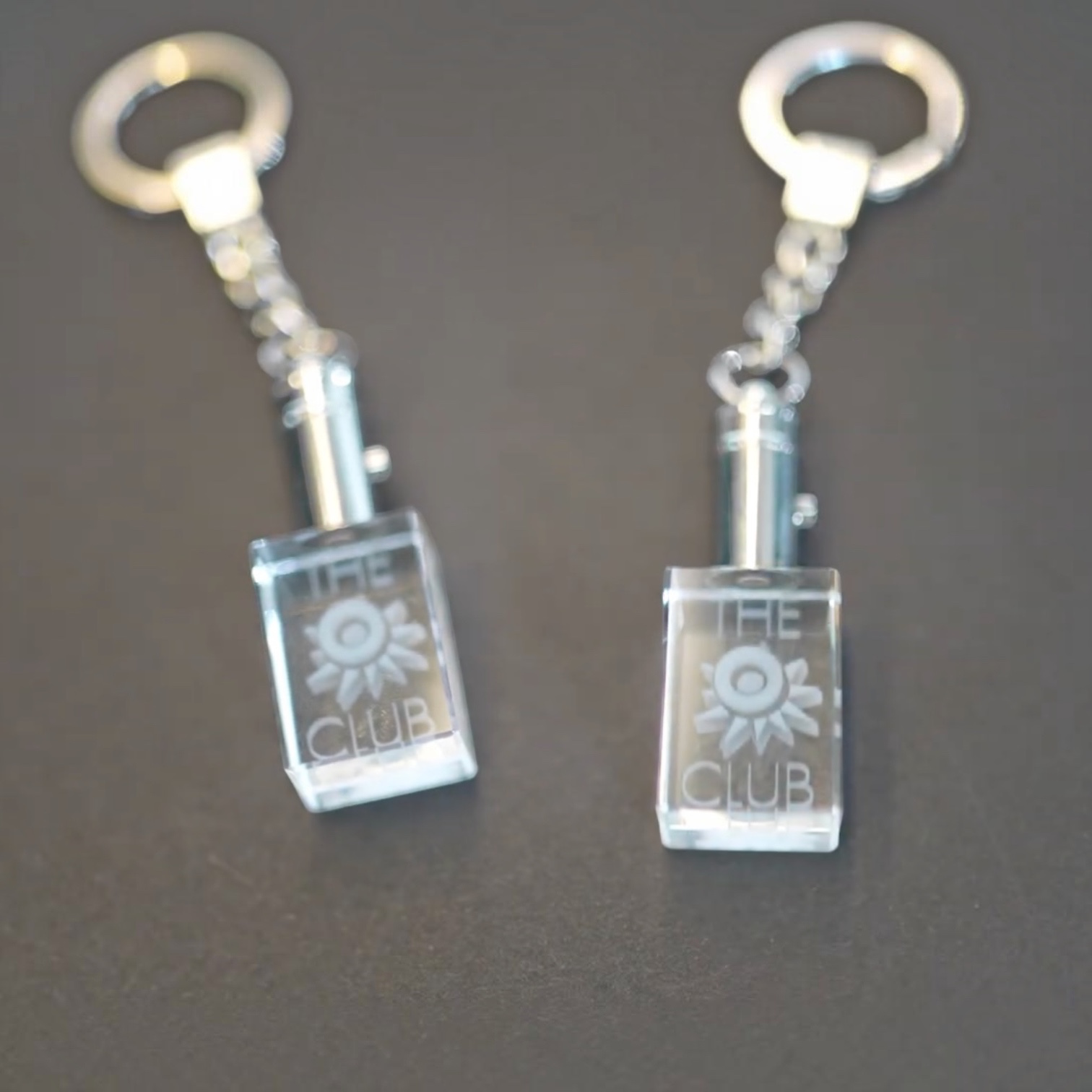 Outrageous Art O Club keychain featuring a clear rectangular crystal block with engraved logo and polished metal chain