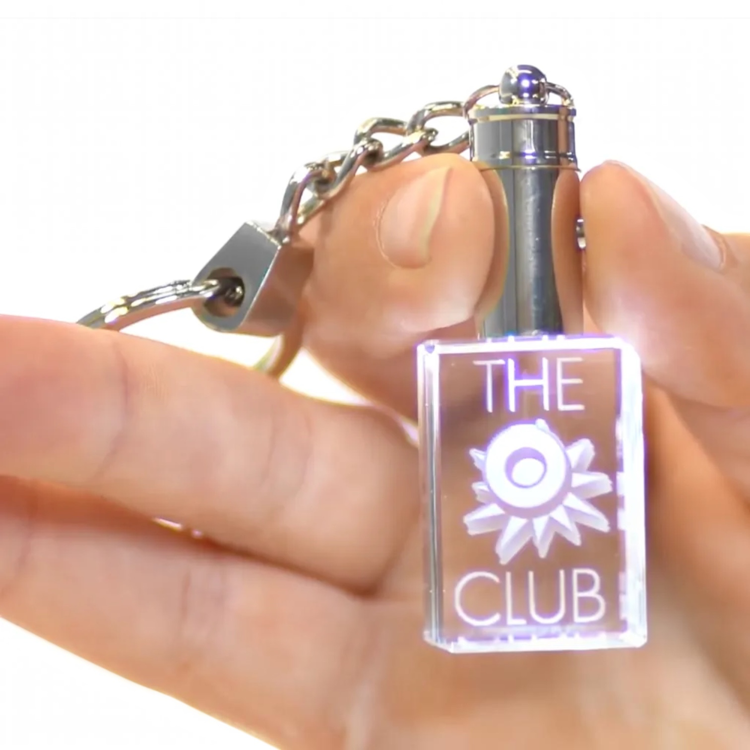 Outrageous Art O Club keychain featuring a glowing rectangular crystal block with metal hardware held in a hand