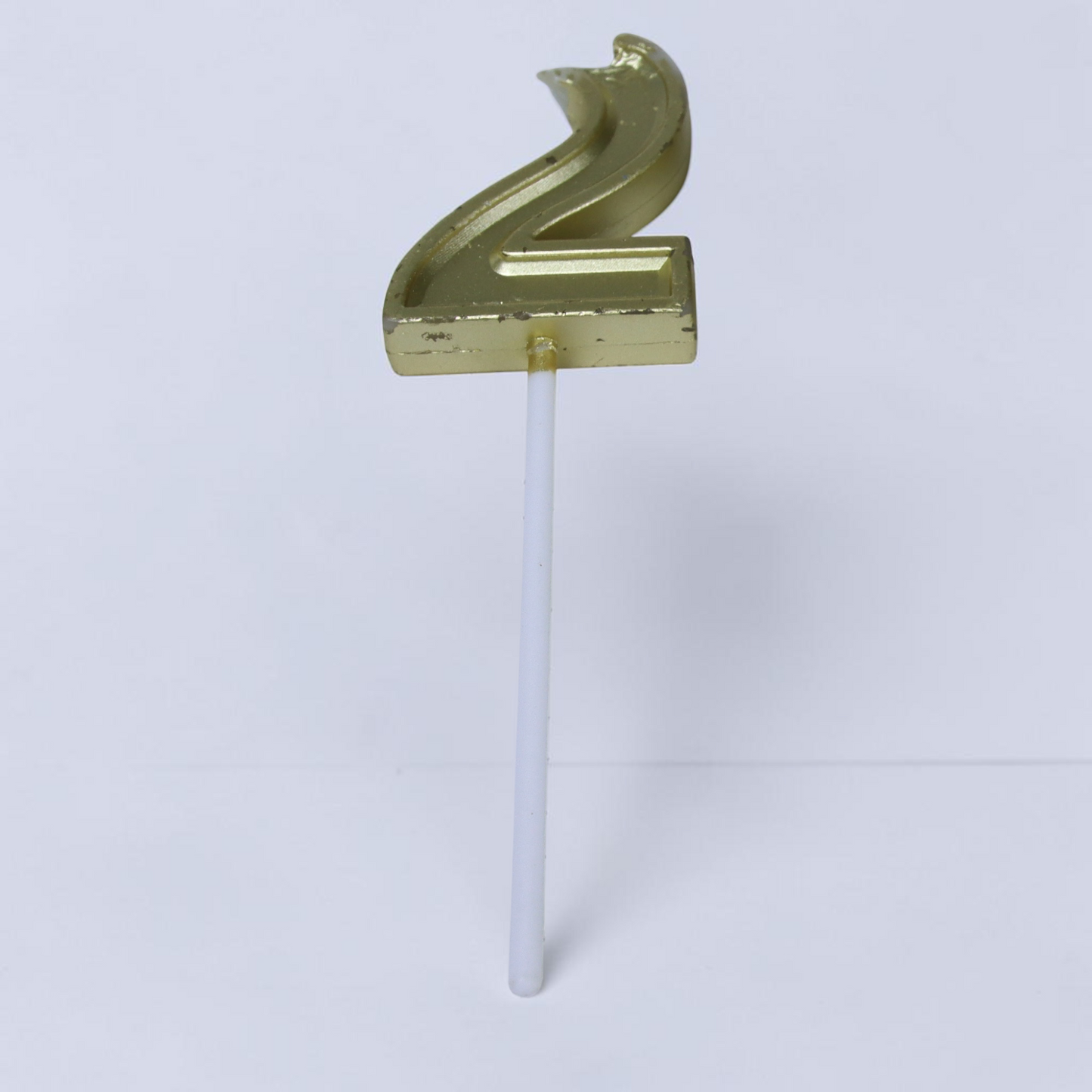 Outrageous Art gold number 2 sculptural candle on a white stick, inspired by Ali Spagnola's video series.