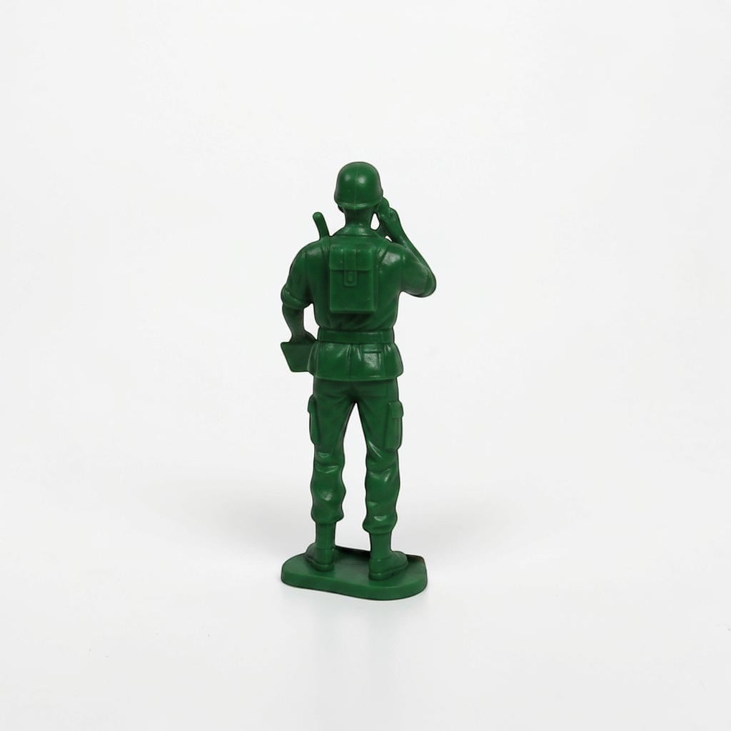 Outrageous Art green plastic toy soldier action figure seen from behind, holding a radio and wearing a backpack.