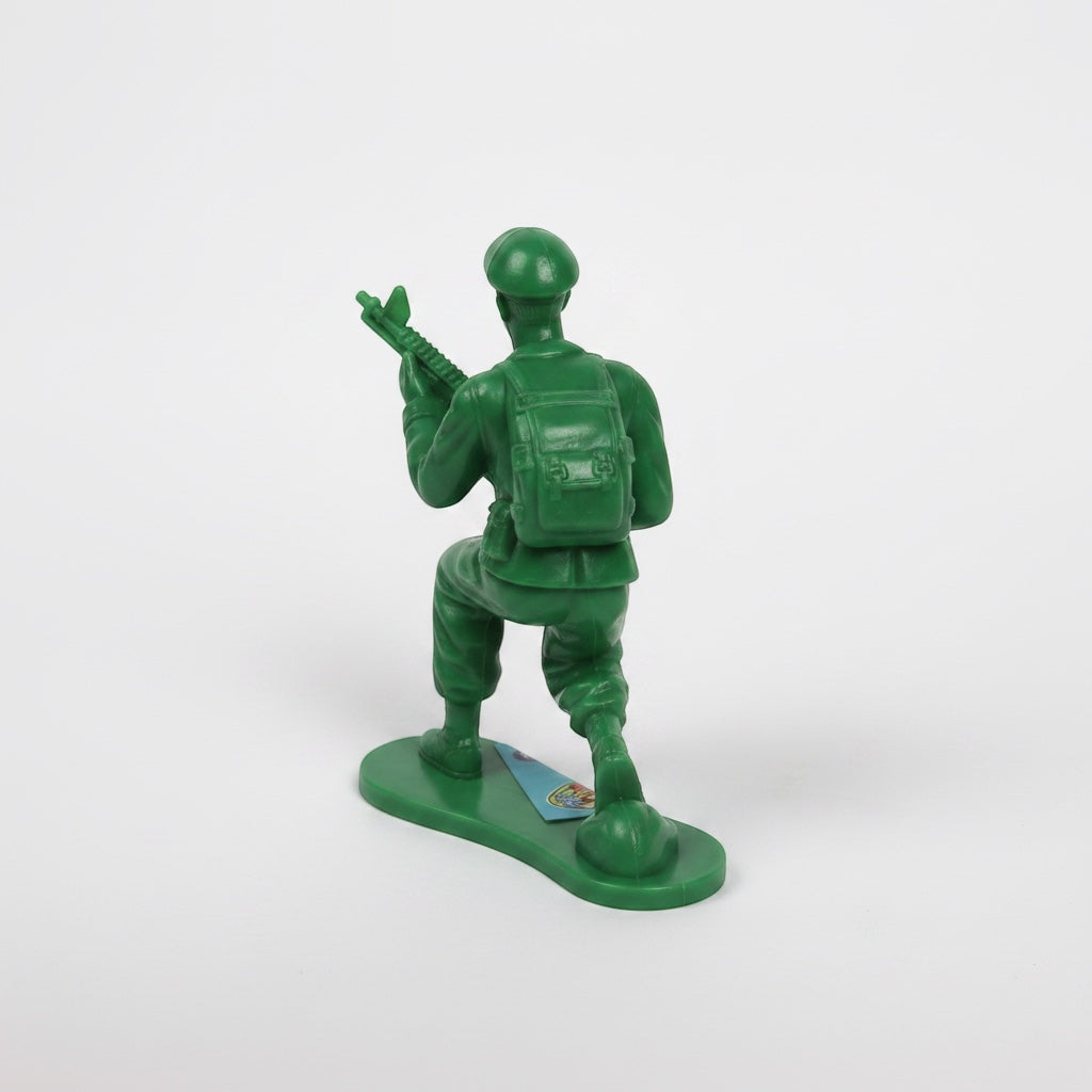 Outrageous Art classic green plastic toy soldier in a kneeling pose with a rifle and backpack on a white background