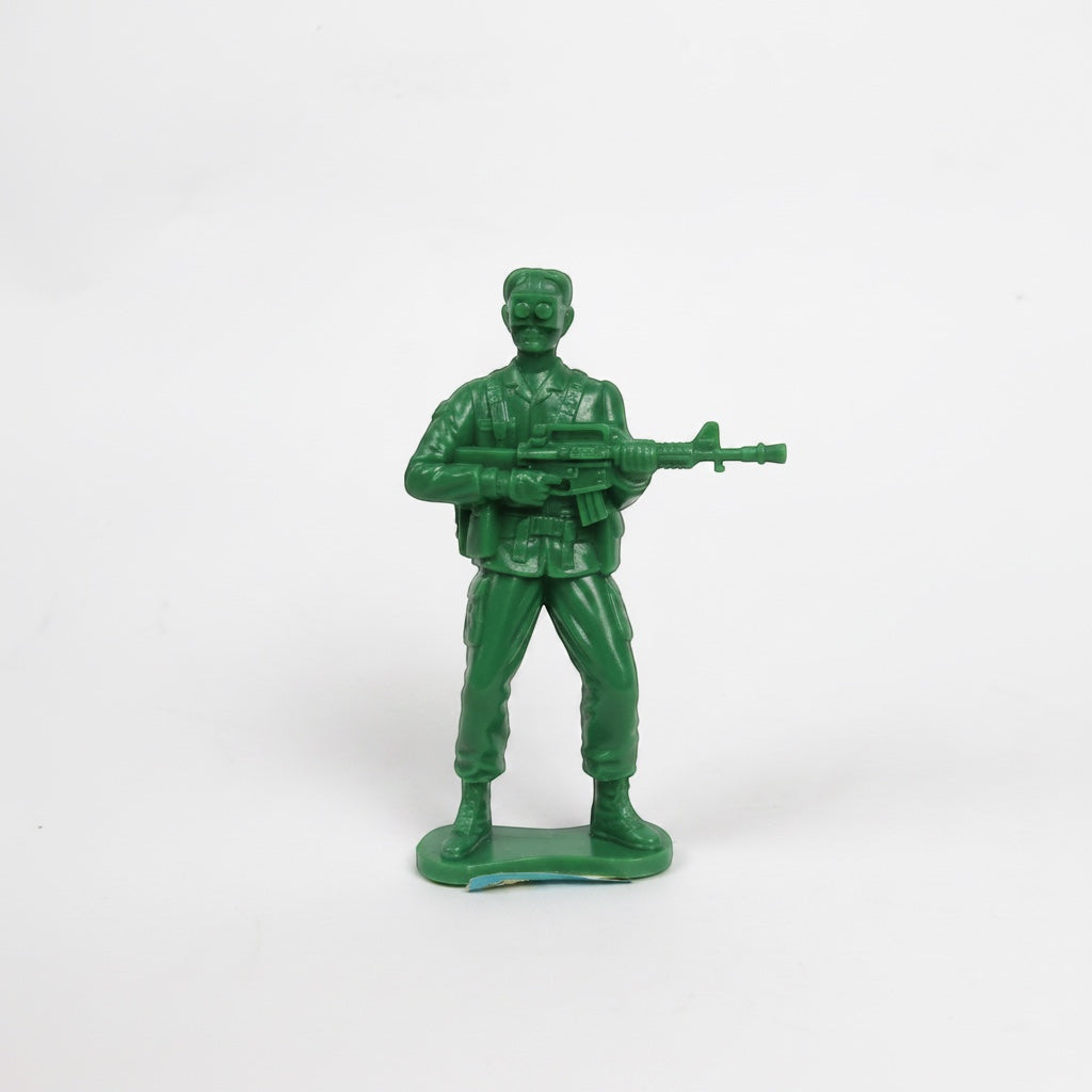 Outrageous Art green plastic toy soldier figurine holding a rifle with goggles and utility belt on a white background