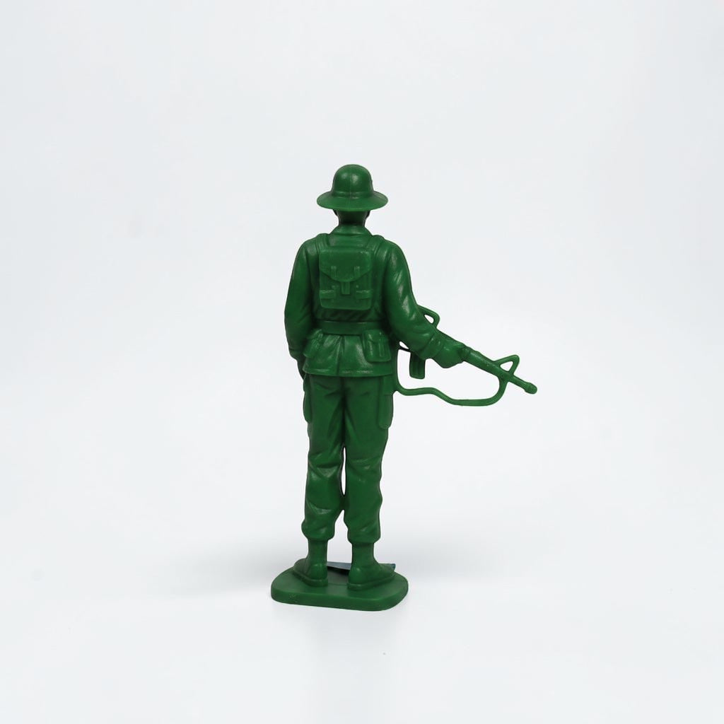 Outrageous Art green plastic toy soldier figurine seen from the back, featuring a rifle and molded uniform details.