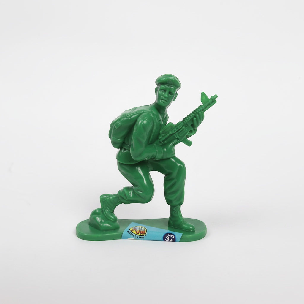 Outrageous Art green plastic toy soldier in a kneeling pose with a rifle and backpack on a white background