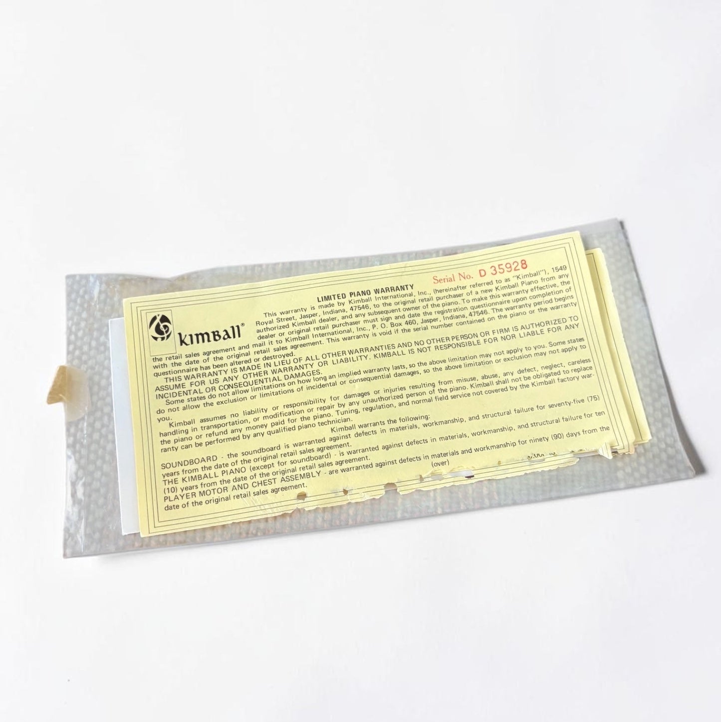 Outrageous Art vintage Kimball Piano limited warranty document with serial number D 35928 on a woven placemat.