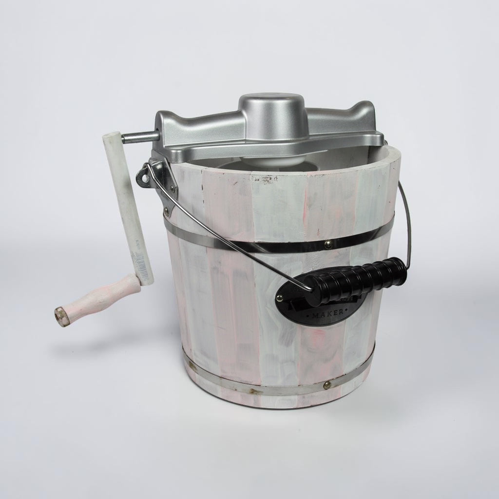 Outrageous Art traditional hand cranked ice cream maker with a distressed white and pink wooden bucket and silver top.