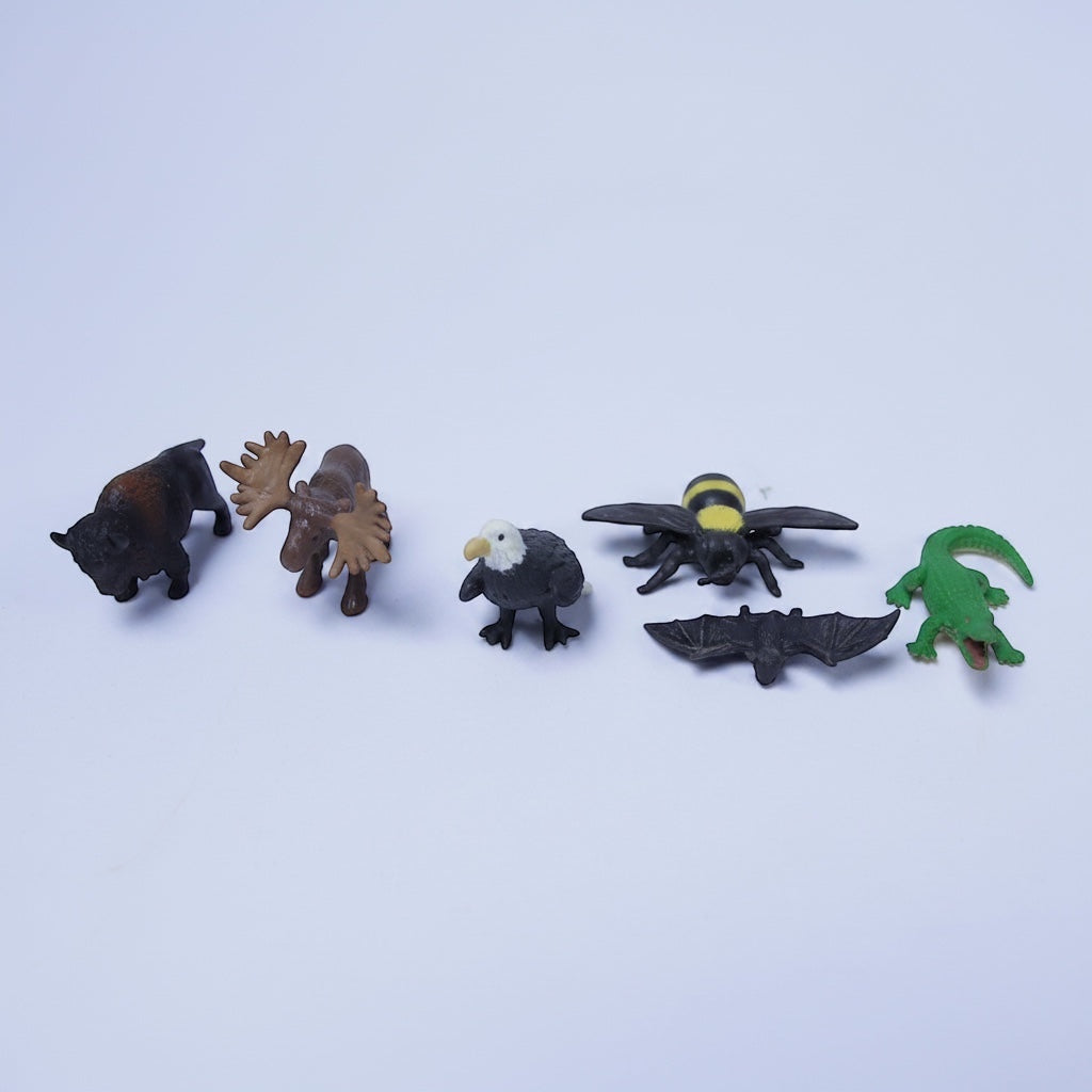 Outrageous Art miniature animal figures including a bumblebee, moose, eagle, bat, and alligator on a white background