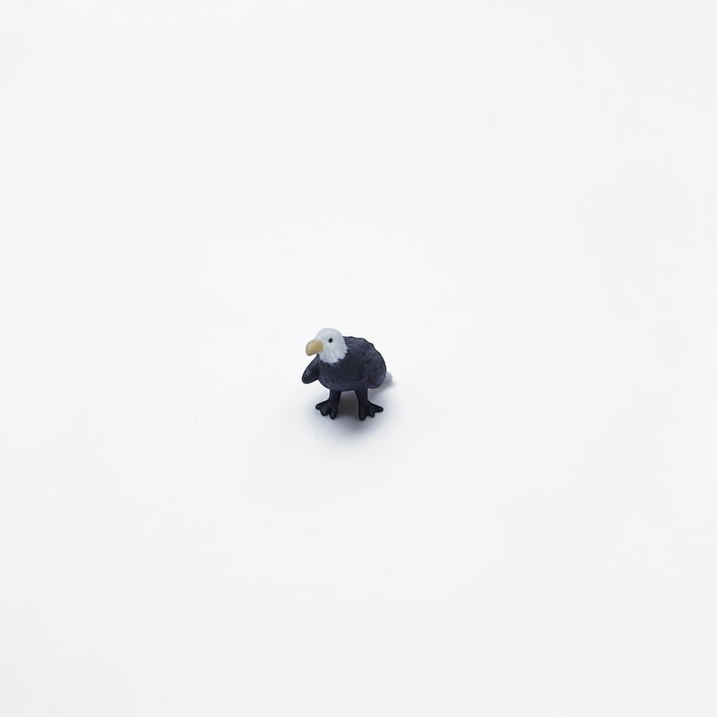 Outrageous Art miniature bald eagle figurine with realistic white head and dark brown body on a white background