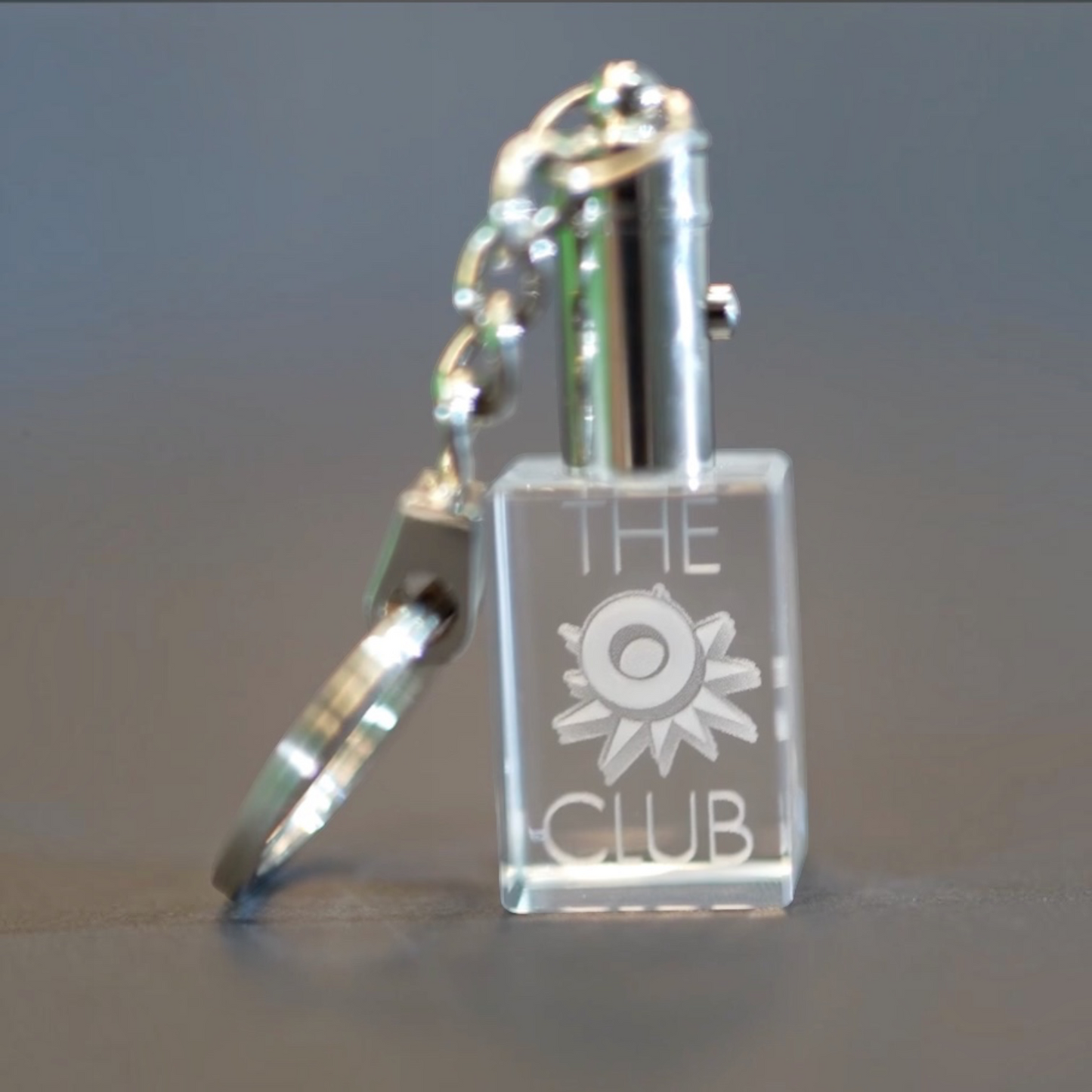 Outrageous Art O Club keychain featuring a clear rectangular acrylic block with engraved logo and polished metal ring