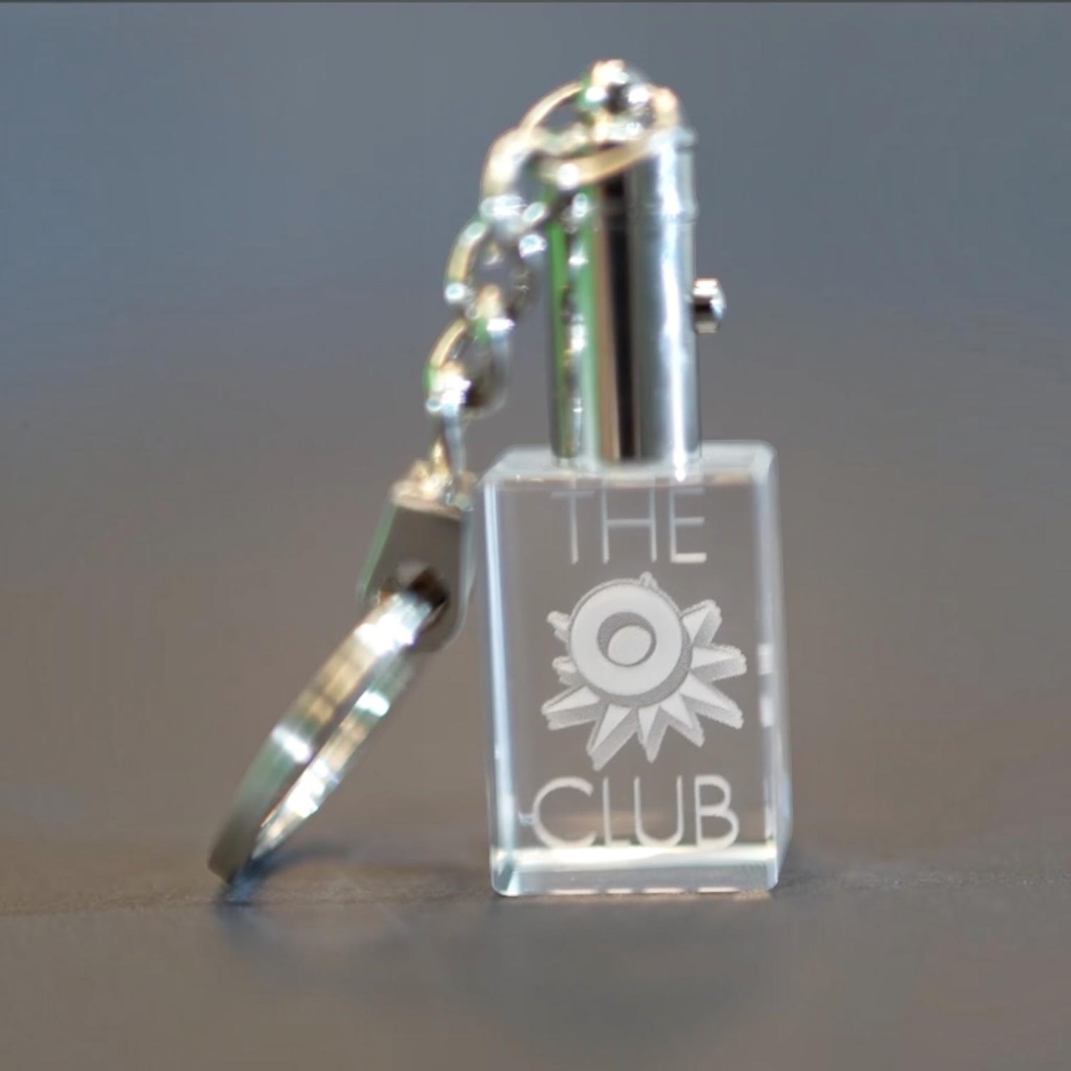 Outrageous Art O Club keychain featuring a clear rectangular acrylic block with engraved logo and polished metal ring