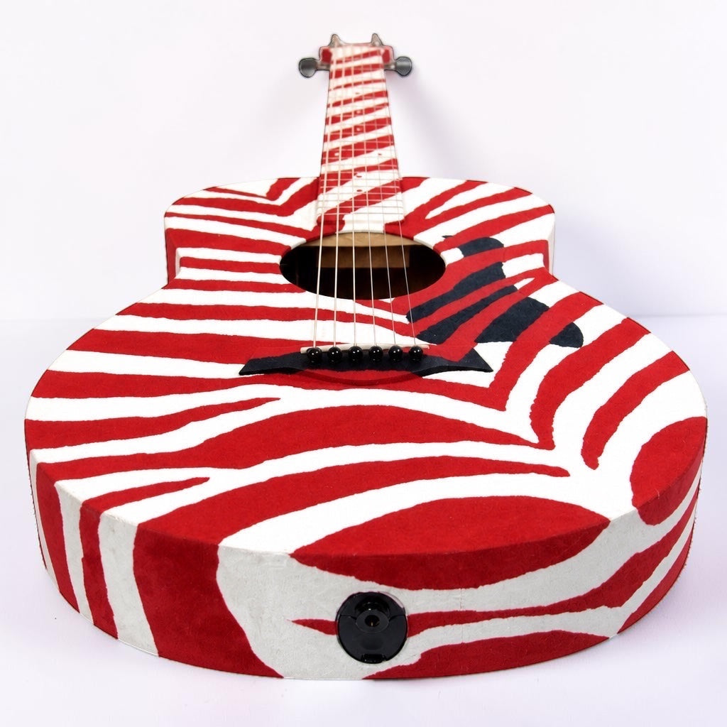 Outrageous Art velvet guitar featuring a bold red and white zebra stripe pattern, front view on white background.