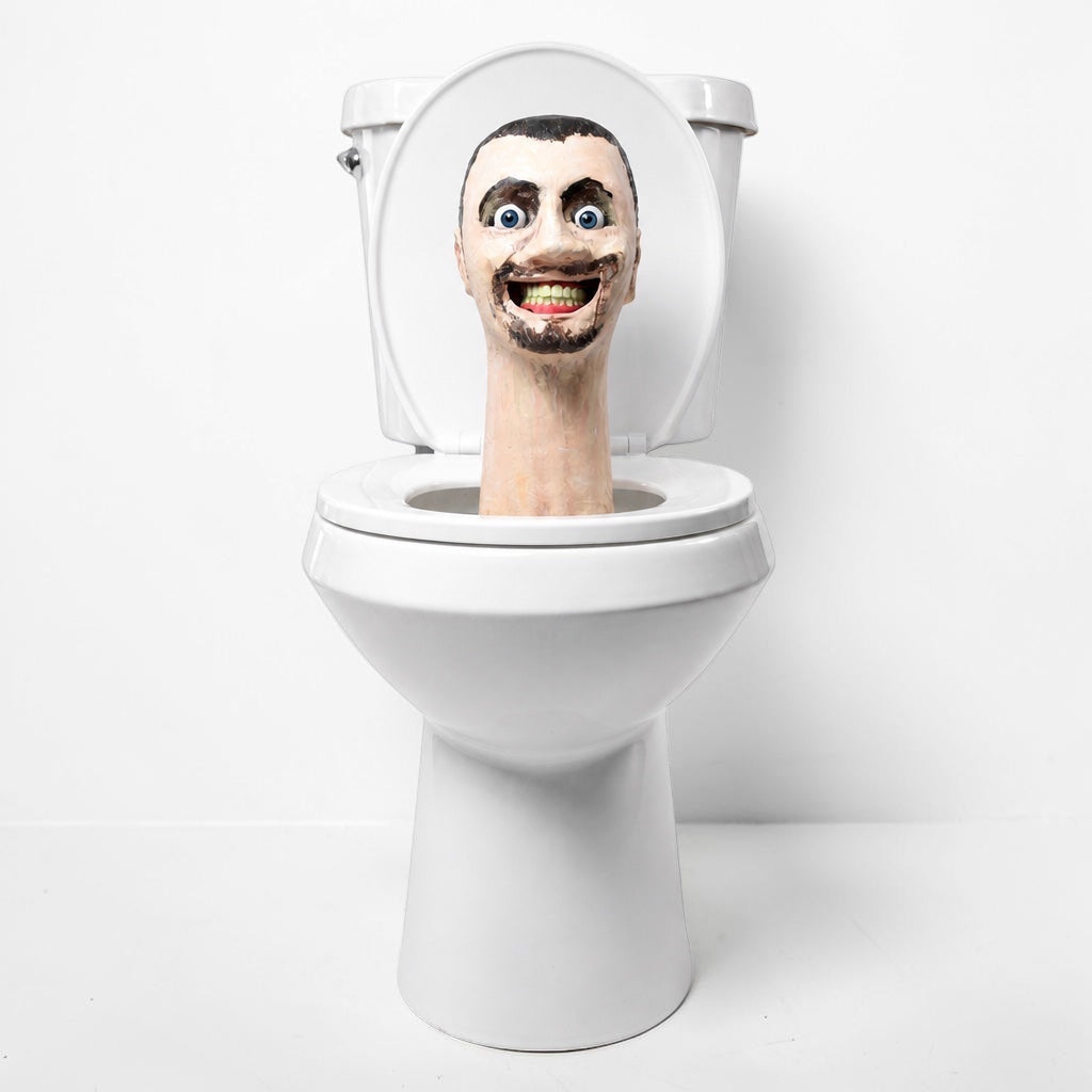 Outrageous Art Skibidi Toilet life-sized sculpture featuring a grinning human head emerging from a white ceramic toilet.
