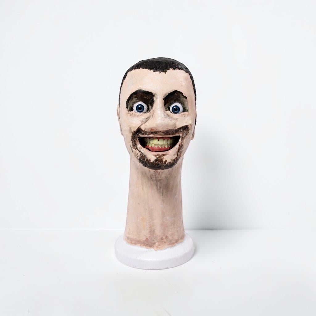 Outrageous Art Skibidi Toilet sculpture featuring a realistic human head with a wide grin on a white base.